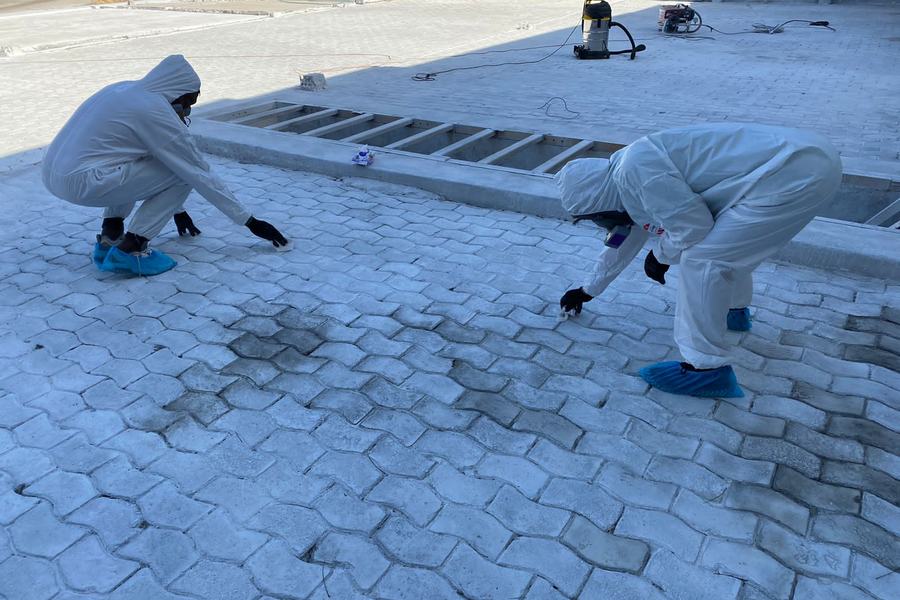 Operarios con traje de protección limpiando cubierta contaminada con asbesto